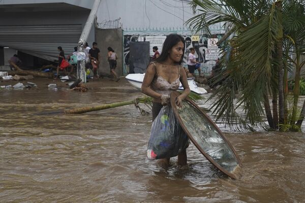 Женщина уходит с вещами, которые она взяла из мебельного магазина после урагана &quot;Отис&quot;, пронесшегося над Акапулько, Мексика, среда, 25 октября 2023 года. - Sputnik Молдова