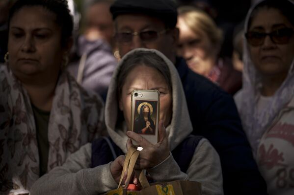 Женщина фотографирует на мобильный телефон, как священники идут во время крестного хода Святого Димитрия, покровителя столицы Румынии, в Бухаресте. Румыния, вторник, 24 октября 2023 года. - Sputnik Молдова