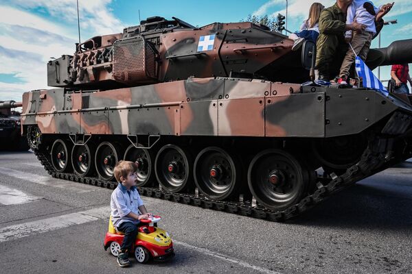 Ребенок сидит в своей машине рядом с боевым танком Leopard 2A6 HEL Сухопутных войск Греции - Sputnik Молдова
