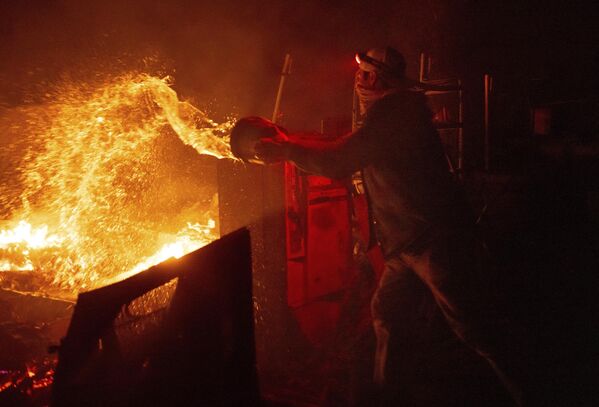 Мужчина тушит пламя лесного пожара в Агуанге, Калифорния. - Sputnik Молдова