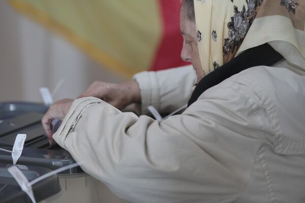 O femeie pune un buletin de vot într-o urna de la o secție de votare din Chișinău. Locuitorii republicii aleg primari ai localităților, precum și membri ai consiliilor raionale, orășenești și sate pentru următorii patru ani. - Sputnik Moldova