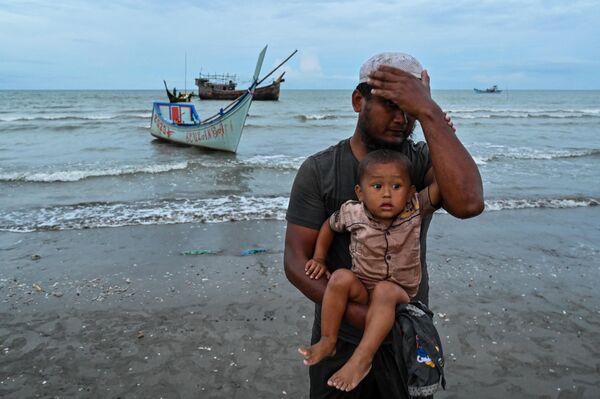 Недавно прибывший беженец рохинджа с ребенком высадился на пляж Бати, провинция Ачех, Индонезия, 15 ноября 2023 года. - Sputnik Молдова