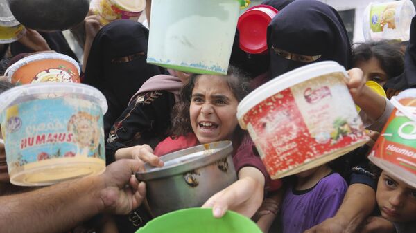 Палестинцы выстраиваются в очередь за едой во время продолжающейся израильской бомбардировки сектора Газа в Рафахе  - Sputnik Moldova