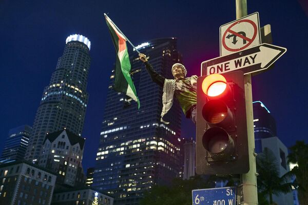 Демонстрант машет палестинским флагом на светофоре во время митинга в центре Лос-Анджелесе - Sputnik Молдова
