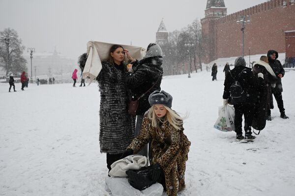 Женщины готовятся позировать для фотосессии на заснеженной Красной площади в Москве. - Sputnik Молдова