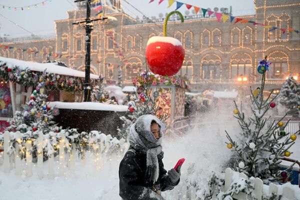 Женщина проходит мимо прилавков Рождественской ярмарки на заснеженной Красной площади в Москве. - Sputnik Молдова