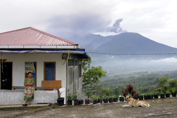 Женщина сидит возле дома на фоне извержения вулкана Мерапи в Агаме, Западная Суматра, Индонезия - Sputnik Молдова