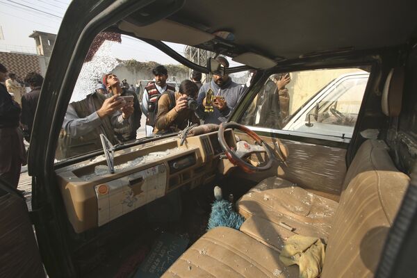 Представители СМИ снимают поврежденный автомобиль на месте взрыва бомбы в Пешаваре, Пакистан - Sputnik Молдова