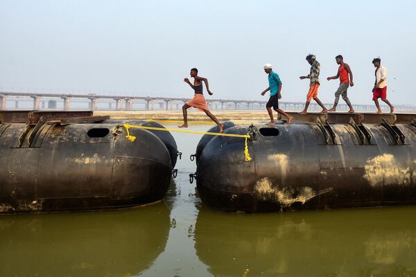Рабочие строят плавучий понтонный мост в преддверии предстоящей ежегодной индуистской религиозной ярмарки Маг Мела вдоль берегов реки Ганг в Праяградже, Индия - Sputnik Молдова