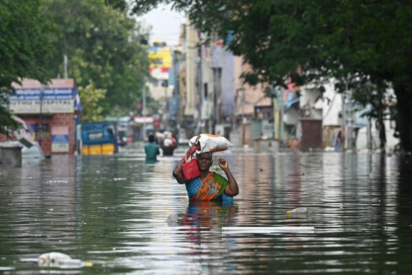 Женщина вместе со своими вещами идет по затопленной улице после проливных дождей в Ченнаи, Индия - Sputnik Молдова