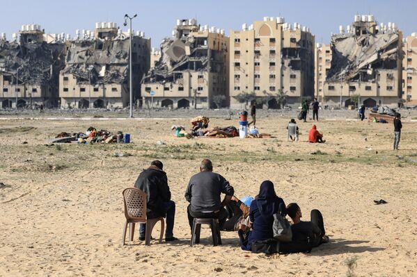 Жители Хан-Юниса в секторе Газа со своими пожитками сидят среди разрушенных домов. - Sputnik Молдова