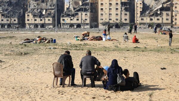 Locuitori ai orașului Gaza, cu ceva bagaje făcute, își privesc casele de locuit distruse de armata Israelului - Sputnik Moldova