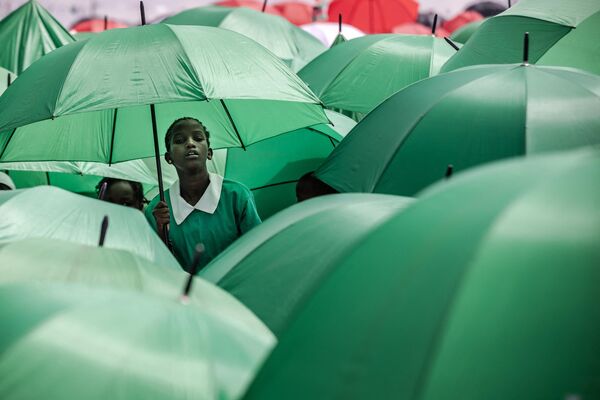 Кенийские студенты держат зонтики, чтобы защитить себя от солнца во время празднования 60-летия независимости Кении, также известного как День Джамхури, в садах Ухуру в Найроби, 12 декабря 2023 года. - Sputnik Молдова