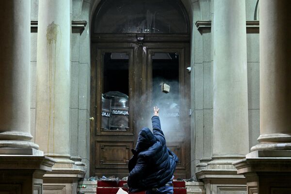 Протестующий бросает снаряд в полицейских, использующих перцовый баллончик, в здании городского совета Белграда, Сербия - Sputnik Молдова