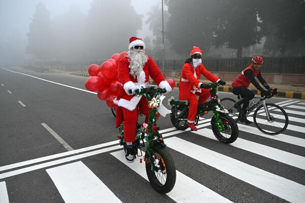 Люди в костюмах Санты едут по улице на Рождество в Нью-Дели  - Sputnik Молдова