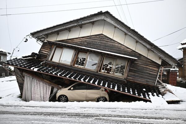 Поврежденный автомобиль лежит под рухнувшим зданием в городе Сика в районе Хакуи префектуры Исикава, 8 января 2024 года, после сильного землетрясения силой 7,5 баллов, произошедшего в регионе Ното в первый день нового года. - Sputnik Молдова