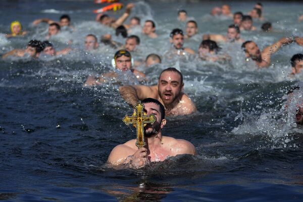 Греческие православные верующие держат деревянное распятие после того, как нашли его в Золотом Роге во время Крещенского дня в Стамбуле, Турция. - Sputnik Молдова