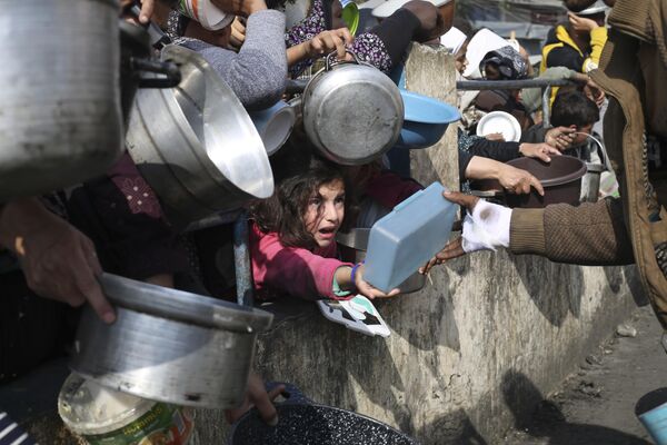 Палестинцы выстраиваются в очередь за бесплатной едой во время продолжающегося израильского воздушного и наземного наступления на сектор Газа в Рафахе. - Sputnik Молдова