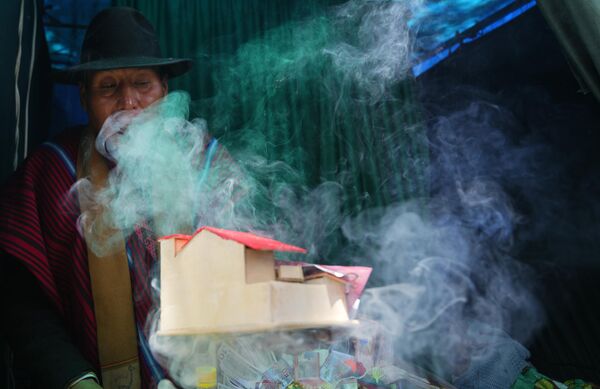 Духовный наставник коренного народа Aymara благословляет миниатюрный дом и банкноты для клиента во время ежегодной ярмарки Alasitas, Боливия, - Sputnik Молдова