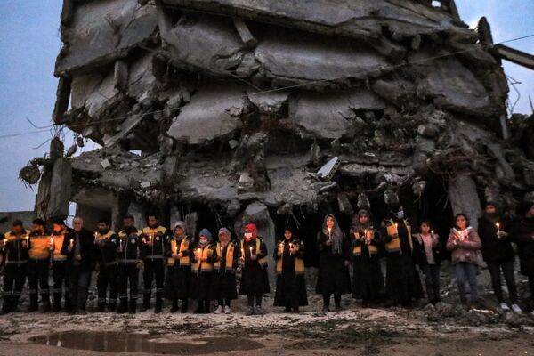 Члены Сирийской гражданской обороны (также известные как &quot;Белые каски&quot;) стоят на пикете памяти с зажженными свечами вместе с выжившими после землетрясения 6 февраля 2023 года, опустошившего северную Сирию и Турцию, отмечая первую годовщину катастрофы. - Sputnik Молдова