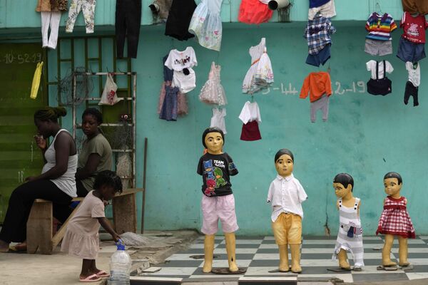 Ребенок играет рядом с манекенами детских размеров возле магазина одежды в Абиджане, Кот-д’Ивуар. - Sputnik Молдова