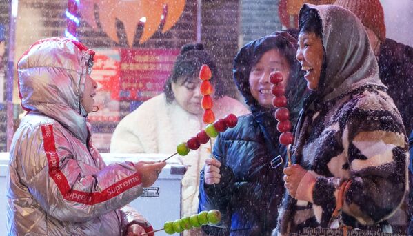 Город Шэньян перед китайским Новым годом. Женщины покупают фрукты в карамели на улице в Шэньяне.  - Sputnik Молдова