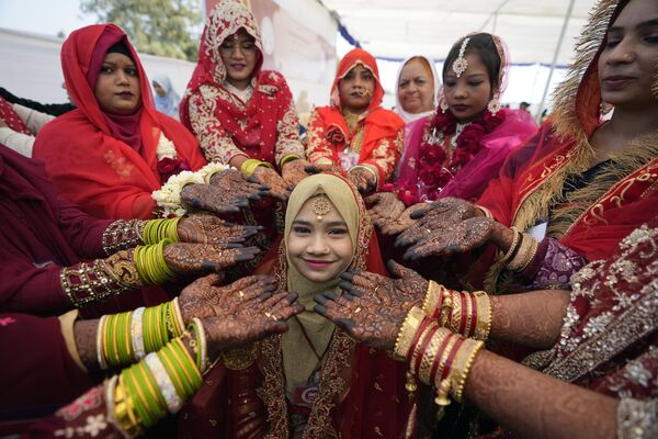 Мусульманские невесты с выкрашенными хной руками окружают другую молодую невесту, когда она позирует для фотографии во время массовой свадьбы в Ахмадабаде, Индия. - Sputnik Молдова