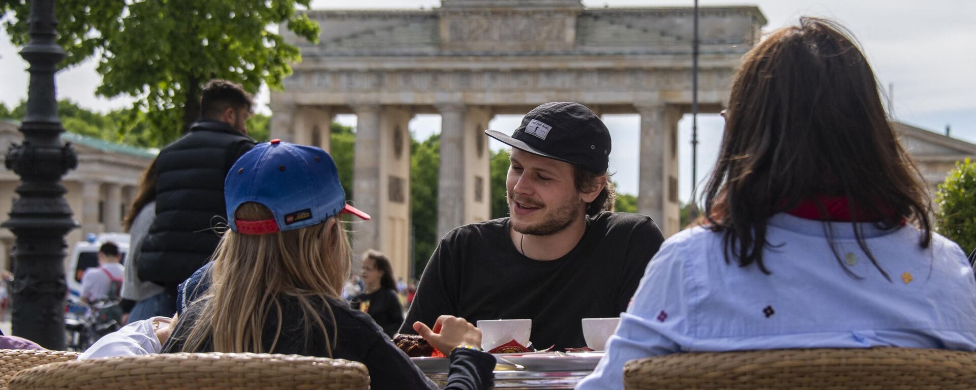 Oameni stau pe terasa unei cafenele de lângă celebra Poartă Brandenburg din Berlin - Sputnik Moldova, 1920, 16.06.2024