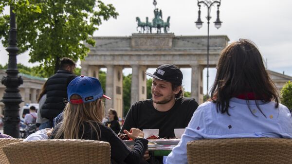 Oameni stau pe terasa unei cafenele de lângă celebra Poartă Brandenburg din Berlin - Sputnik Moldova