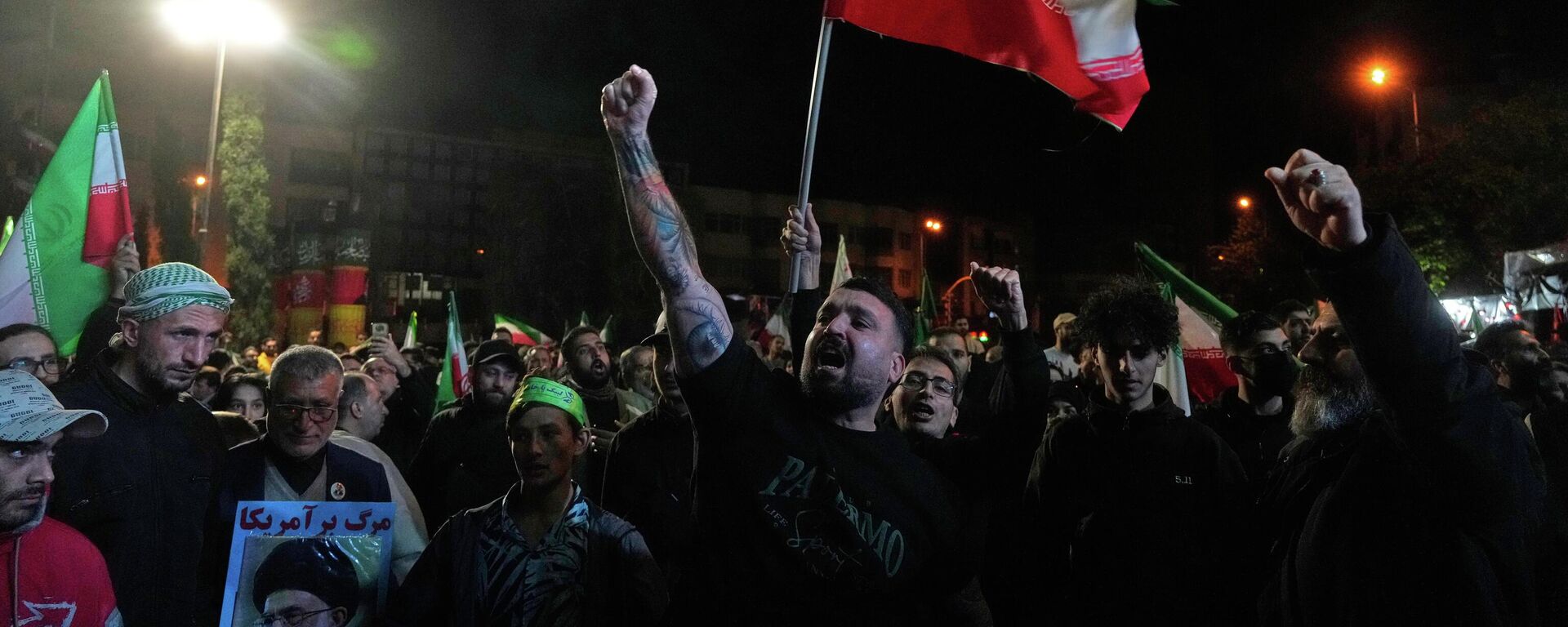 Проправительственные демонстранты скандируют лозунги, держа в руках иранские флаги и плакат с изображением покойного верховного лидера аятоллы Али Хаменеи - Sputnik Молдова, 1920, 08.04.2026