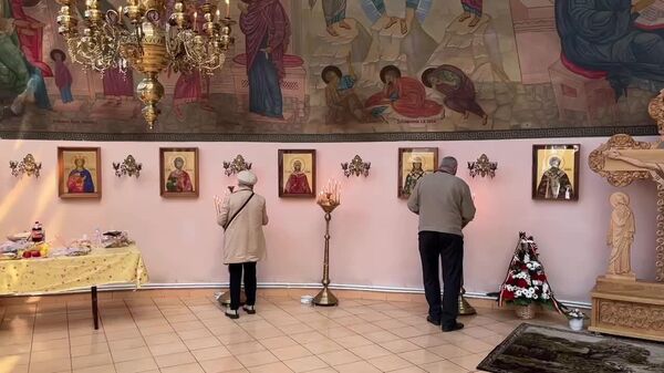 Участники торжественной церемонии у памятника участникам ликвидации аварии на Чернобыльской АЭС зажигают свечи в память об ушедших из жизни — в храме, расположенном на территории мемориала - Sputnik Молдова