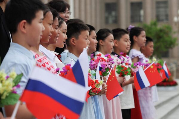 Дети, держащие российский и китайский флаги, позируют для фотографии перед церемонией приветствия президента России Владимира Путина в Большом зале народа в Пекине. - Sputnik Молдова