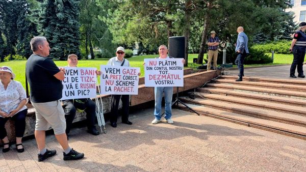 Протестующие держат в руках плакаты "Нам нужен газ по правильным ценам, а не тем, какие у вас в схемах". - Sputnik Молдова