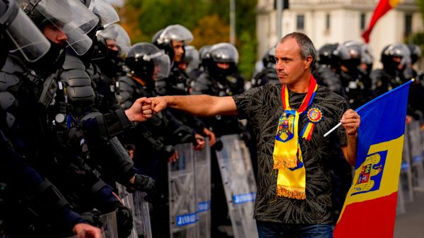 Участник акции протеста фермеров в Бухаресте (Румыния) приветствует сотрудника спецподразделения полиции  - Sputnik Молдова