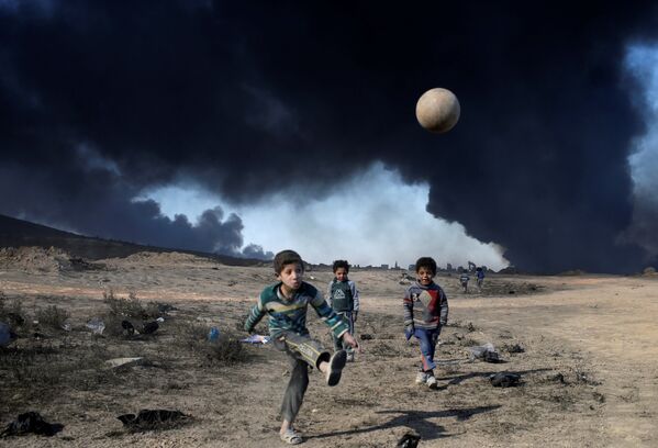 Футбол на окраине иракского города Кайяра на фоне пожаров на нефтехранилищах террористической группировки Исламское государство (ИГ, запрещена в РФ). - Sputnik Молдова