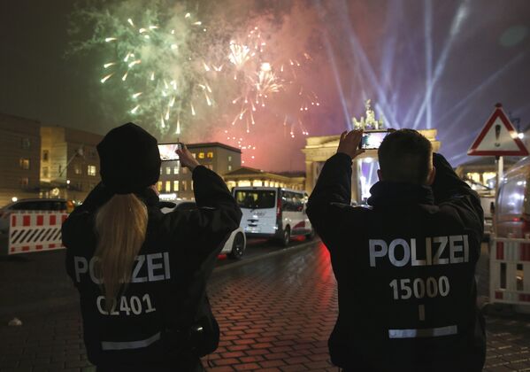 Немецкие полицейские снимают, как новогодний фейерверк взрывается рядом со скульптурой колесницы на Бранденбургских воротах во время Новогодних торжеств в Берлине, Германия. 1 января 2017 года - Sputnik Молдова