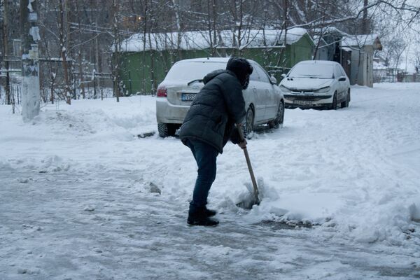 Oamenii curăță singuri zăpada de prin curți, deoarece mersul devine tot mai anevoios. - Sputnik Moldova