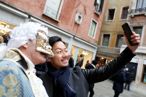 Un turist își face un selfi cu un participant la carnavalul de la Veneția. - Sputnik Moldova