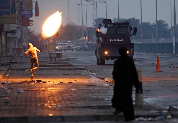 Протестующий бросает бутылку с зажигательной смесью во время протеста в Бахрейне. - Sputnik Молдова
