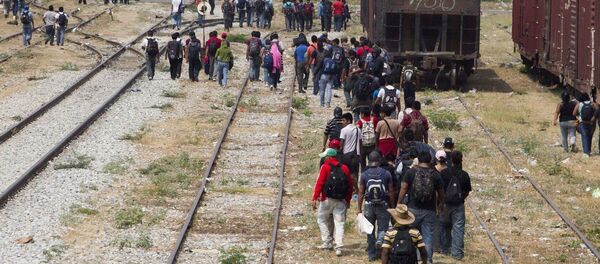 Immigrants walk along the rail tracks after getting off a train during their journey toward the US-Mexico border in Ixtepec, southern Mexico Immigrants walk along the rail tracks after getting off a train during their journey toward the US-Mexico border in Ixtepec, southern Mexico - Sputnik Moldova