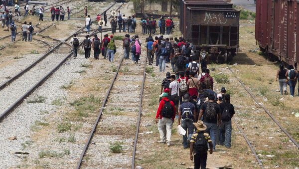Immigrants walk along the rail tracks after getting off a train during their journey toward the US-Mexico border in Ixtepec, southern Mexico - Sputnik Moldova