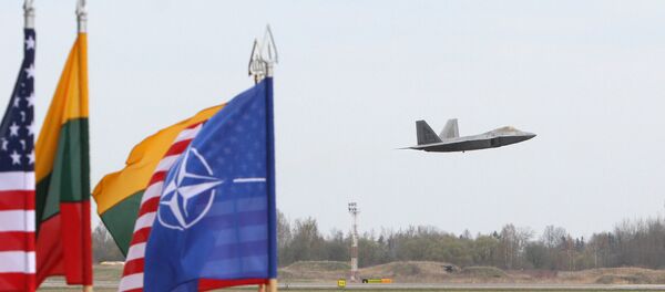 A US Air Force F-22 Raptor fighter aircraft flies at the Air Base of the Lithuanian Armed Forces in Šiauliai, Lithuania, on April 27, 2016 behind flags of US, Lithiania and the NATO - Sputnik Moldova-România