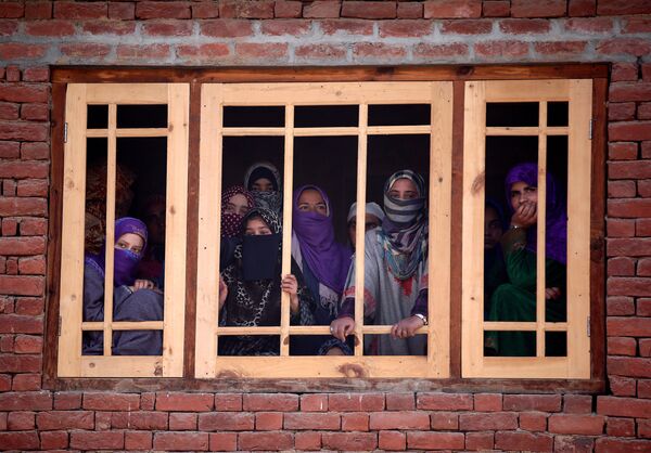 Женщины-мусульманки смотрят из окна на похороны Райеда Ахмада Вани в деревне Беллоу на юге Кашмира. По сообщениям СМИ, Райед Ахмад Вани был убит в Падгампоре во время столкновения с индийскими силами безопасности - Sputnik Молдова