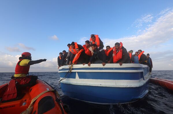Испанские спасатели помогают мигрантам, плывущим на деревянном судне в Средиземном море у побережья Ливии - Sputnik Молдова