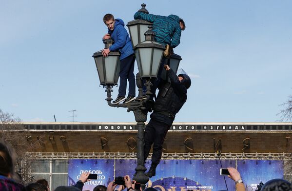 Сотрудник правоохранительных органов взбирается на фонарный столб, чтобы задержать участников несанкционированного митинга против коррупции в Москве, Россия - Sputnik Молдова