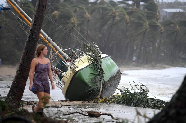 Жительница Австралии проходит мимо яхты, которая была выброшена на берег во время циклона Дебби в городе Квинсленд. Сила ветра во время стихийного бедствия в Австралии достигала 263 км в час - Sputnik Молдова