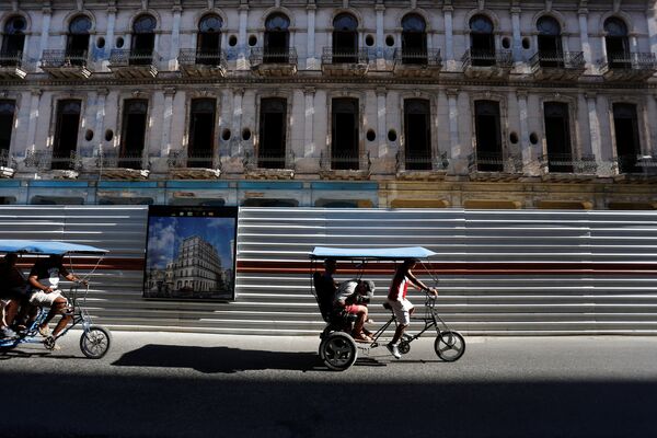 Велотакси проезжают мимо исторического здания, в котором проходят реставрационные работы в Гаване, Куба. Велорикши - это недорогой и очень распространенный в кубинской столице вида общественного транспорта - Sputnik Молдова