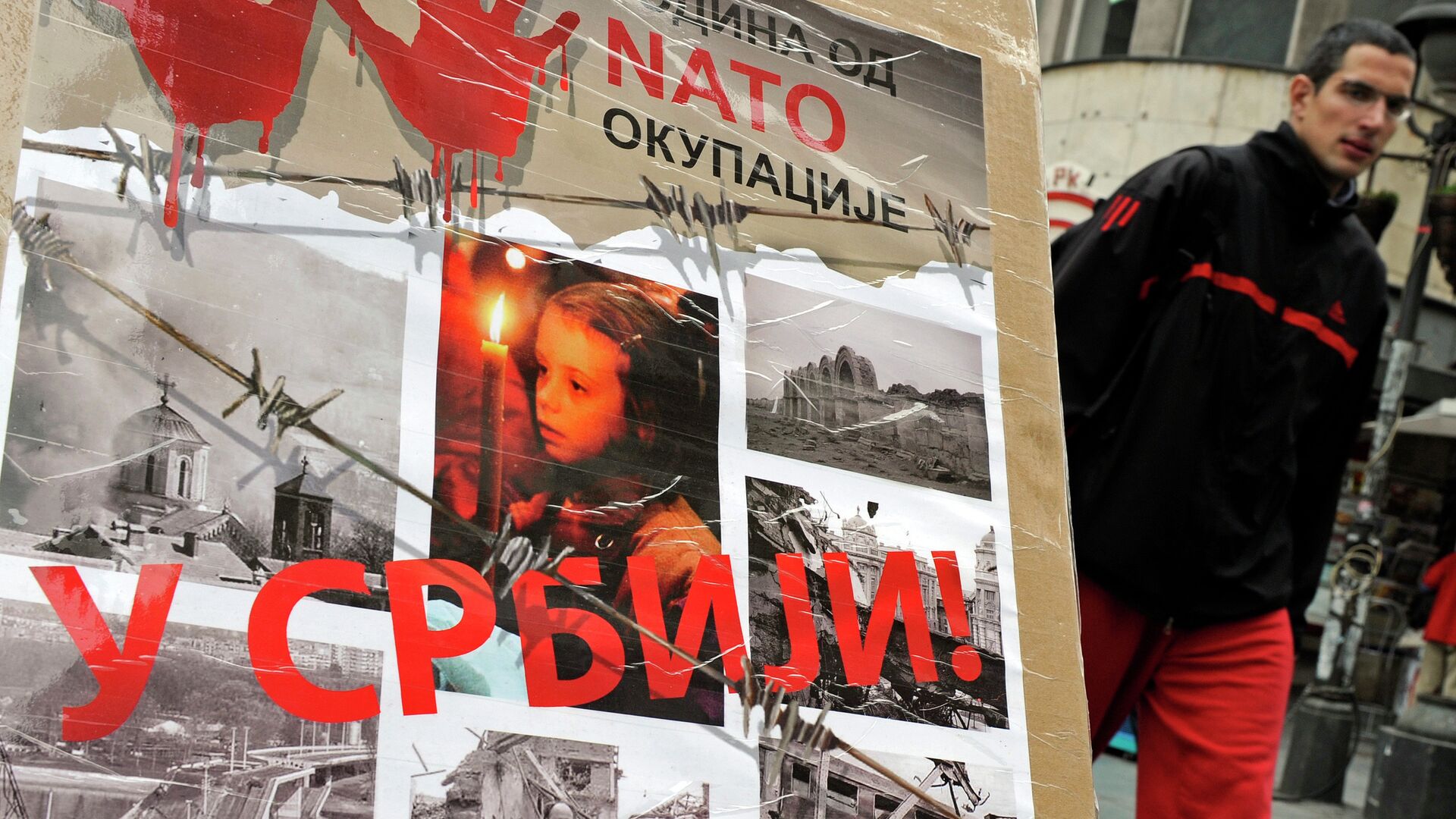A man walks past a poster with the reading “Ten years of NATO occupation of Serbia”, and displaying images from 1999 NATO air campaign against Serbia and Montenegro, in Belgrade on March 23, 2009.  - Sputnik Moldova, 1920, 04.08.2021