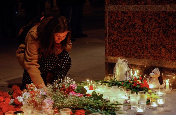 Девушка зажигает свечу у входа в вестибюль станции метро Спасская в память о погибших в результате взрыва в метрополитене Санкт-Петербурга - Sputnik Молдова