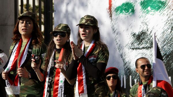 Syrian pro-regime supporters dressed in military uniform stand in front of a mural of President Bashar al-Assad during a rally in Damascus. File photo - Sputnik Moldova-România